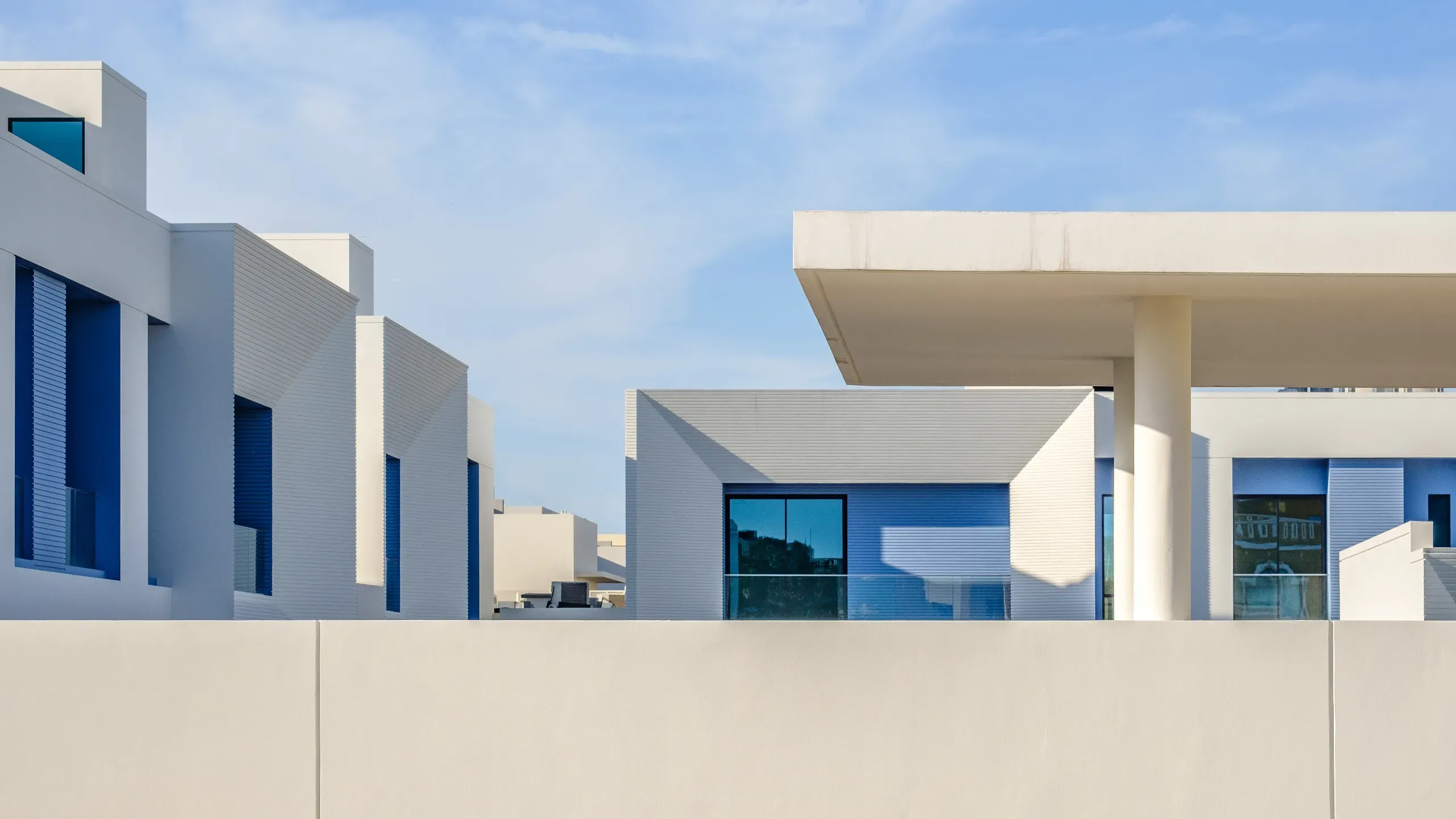 Modern minimalist luxury villas in a high-end Bahrain housing development with clean lines and blue accents.