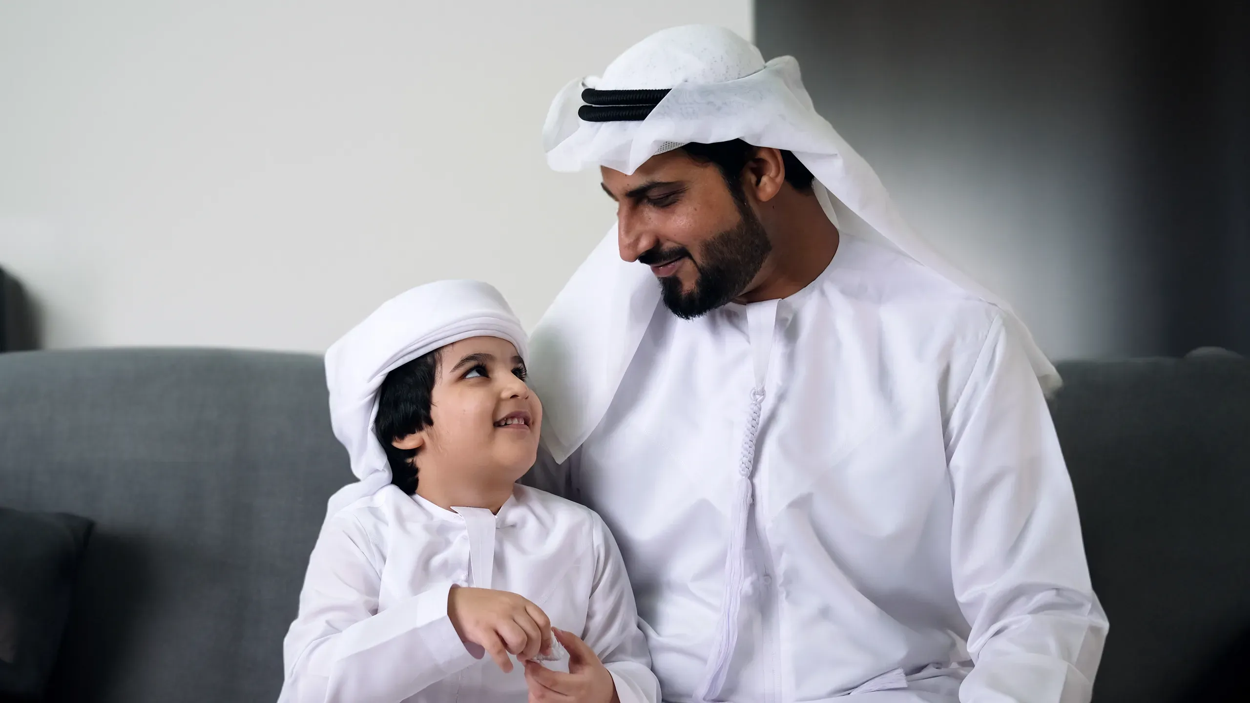 Father and son in traditional white thobes, representing Bahraini cultural identity and family life in a luxury residential setting.