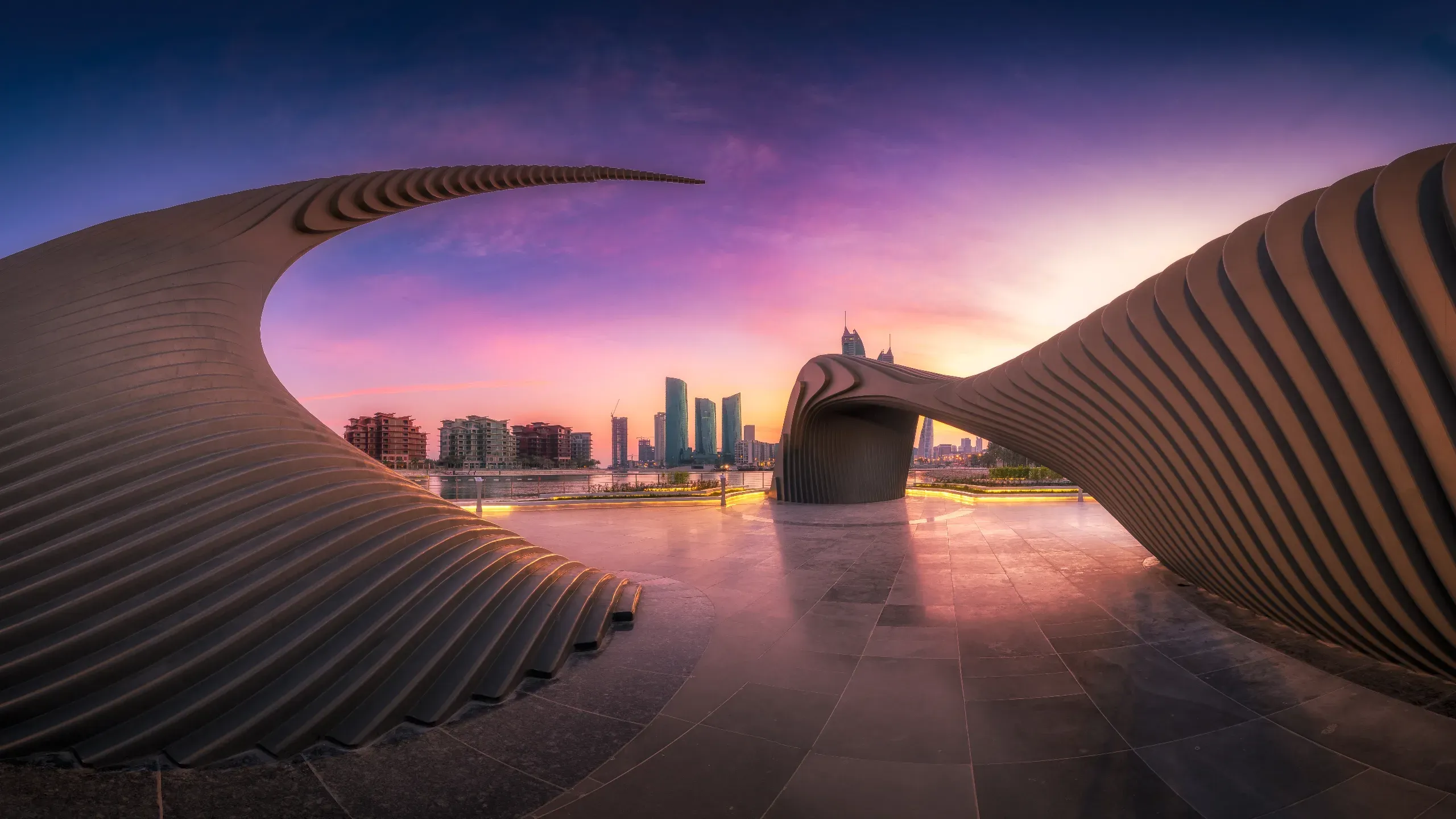 Athar Monument at sunset, a symbolic architectural tribute to Bahraini women with the vibrant Manama skyline in the background.