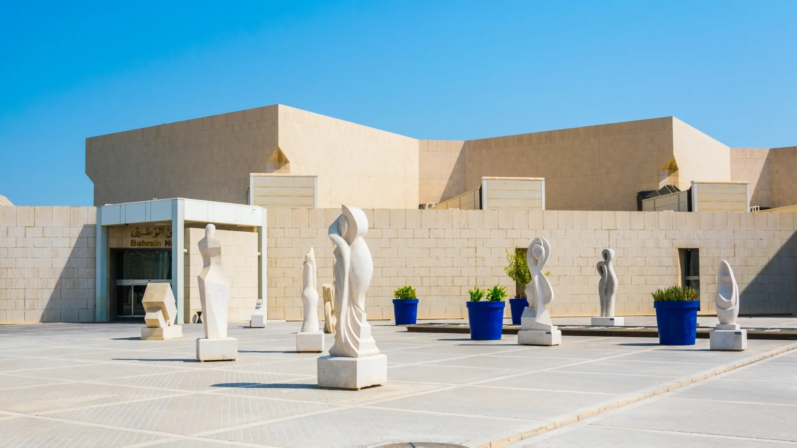 Bahrain National Museum waterfront exterior in Manama, featuring modern architecture and contemporary outdoor sculptures.