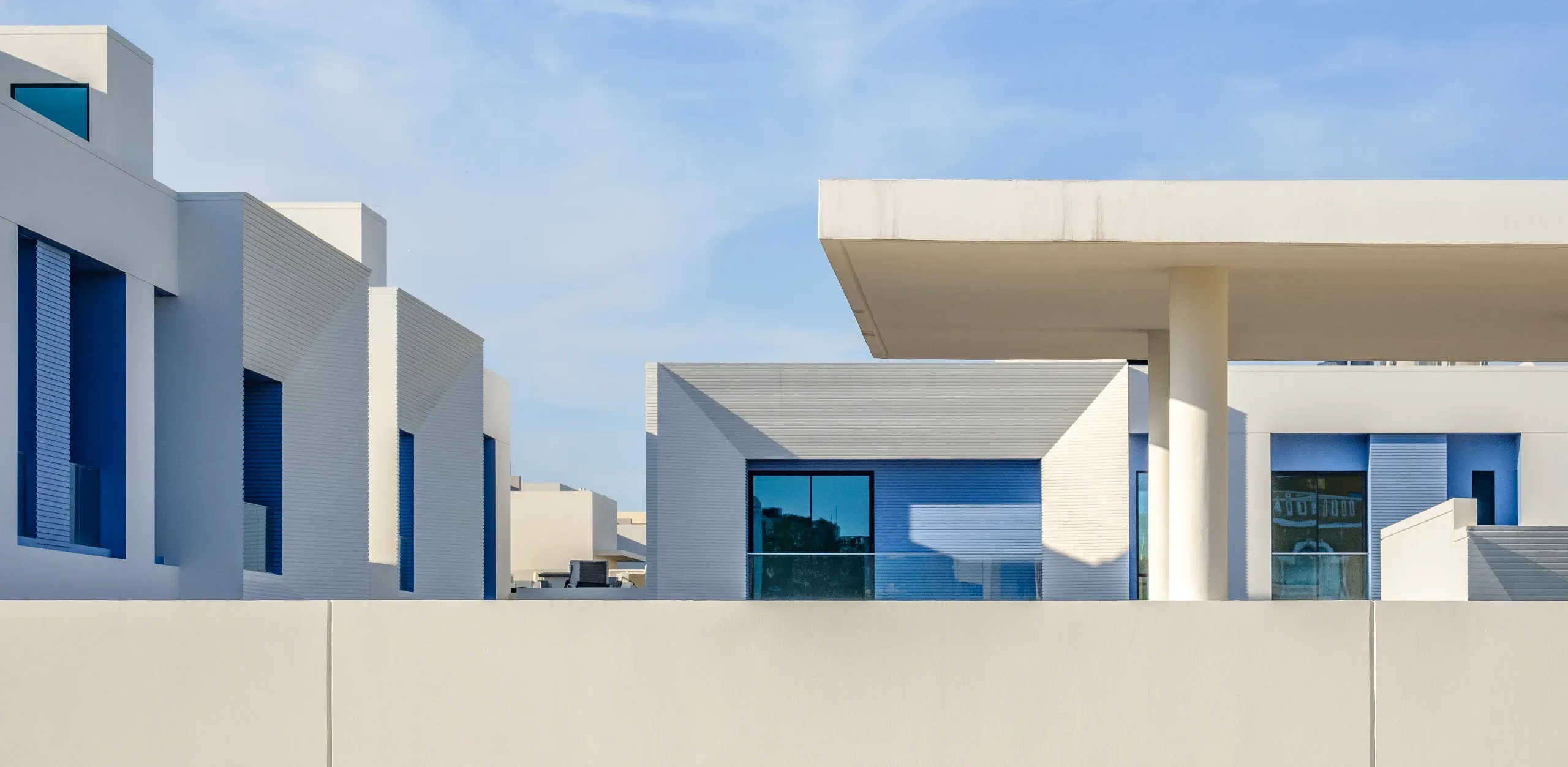 Modern minimalist luxury villas in a high-end Bahrain housing development with clean lines and blue accents.