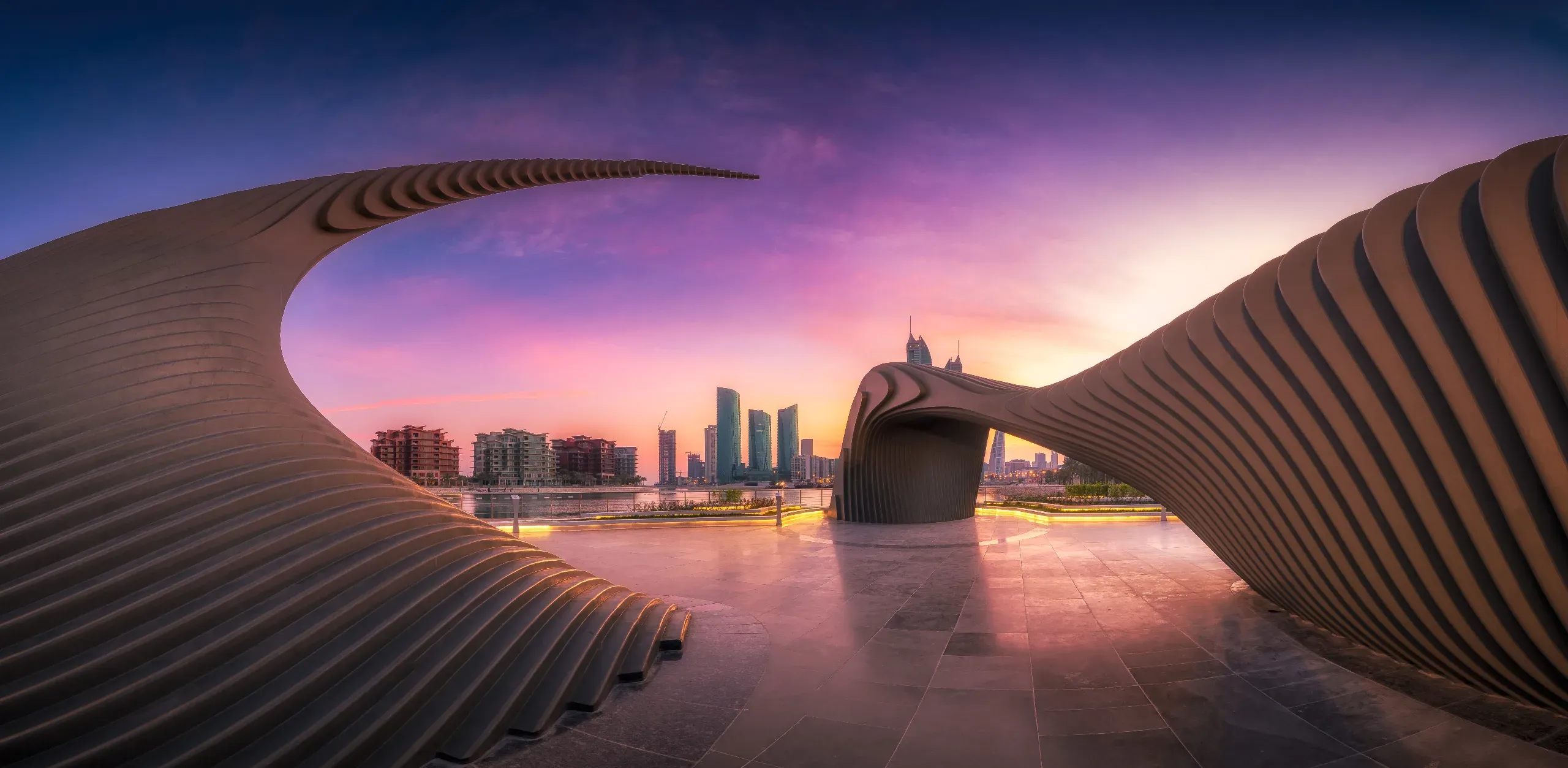 Athar Monument at sunset, a symbolic architectural tribute to Bahraini women with the vibrant Manama skyline in the background.