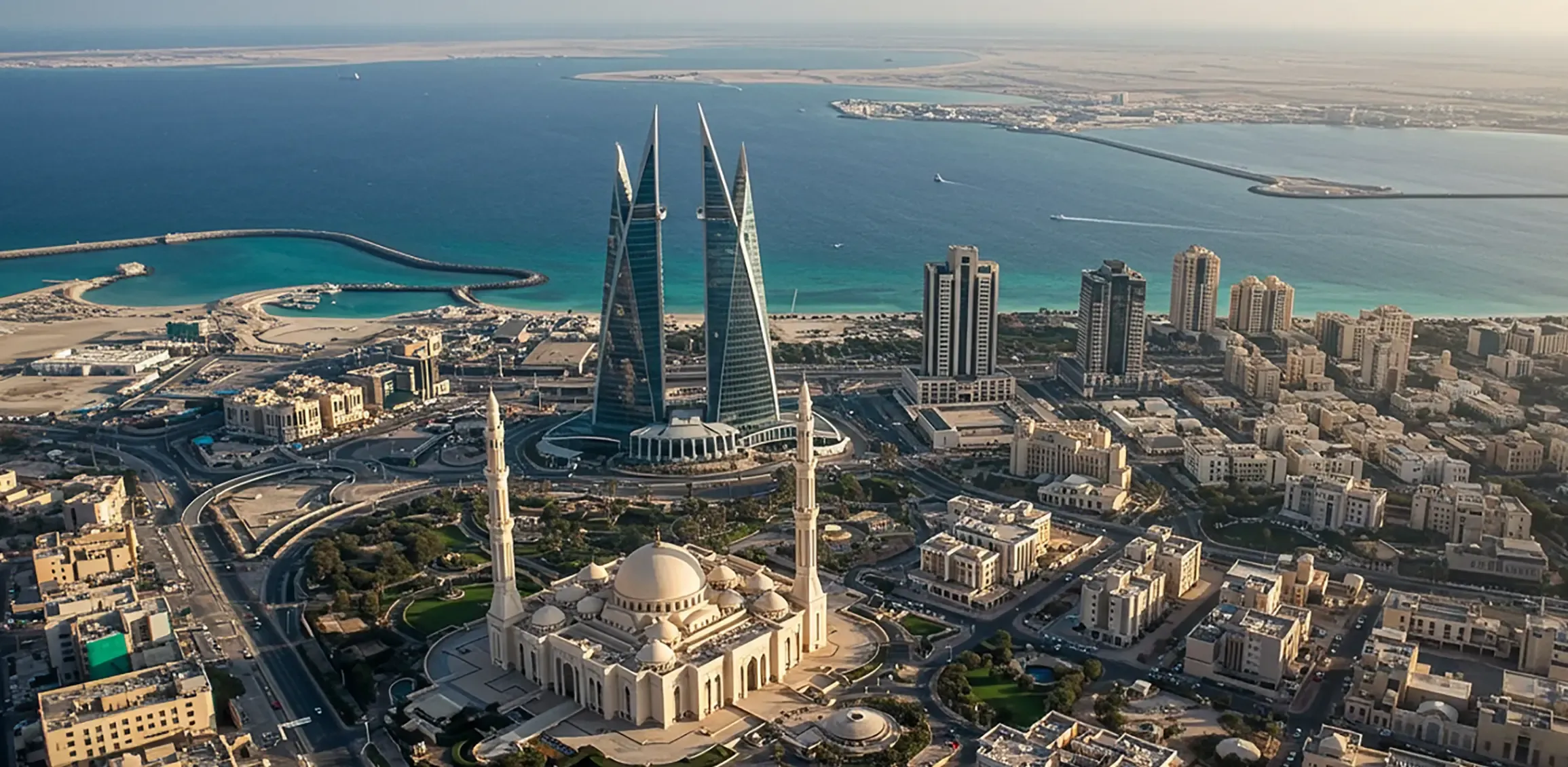 Aerial view of Manama city featuring Al Fateh Grand Mosque in the foreground and the iconic Bahrain World Trade Center towers. 